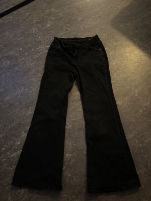 Svarta bootcut jeans - Säljer ett par svarta jeans med bootcut passform. Klassisk femficksmodell med knapp och dragkedja framtill. Jeansen har en snygg utsvängd siluett och är tillverkade i ett mjukt denimtyg som sitter skönt hela dagen. Bara använda ett par gånger 