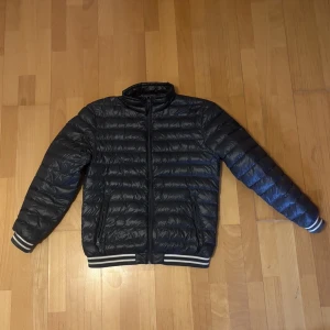 Svart pufferjacka med randiga muddar - Säljer en mörkgrön tunn pufferjacka från Esprit. Köptes av någon annan på denna plattform ett tag sen men har ej haft användning till jackan på sistone därmed säljer jag vidare den. Vid fler frågor hör av dig!