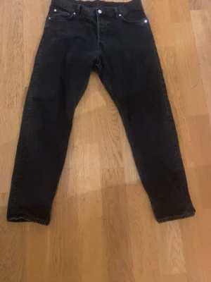 Weekday jeans - Svarta jeans från Weekday i klassisk femficksmodell. Jeansen har rak passform och är tillverkade i bomullsmaterial. Snyggt stilrena med svarta sömmar och knappstängning framtill. Perfekta för dig som gillar enkel och clean look.