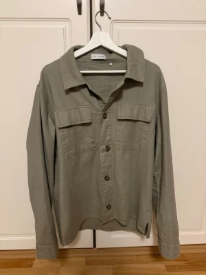 Grön overshirt från Axiome, strl 48 - En unik grön overshirt från Axiome i storlek 48. Jackan är köpt i Belgien och nypris ligger på 1300. Den är sparsamt använd och färgen får dig verkligen att sticka ut. Om du undrar något är det bara att skriva :)