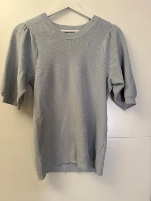 Ljusblå stickad tröja med puffärm - Snygg ljusblå stickad tröja med puffiga kortärmar och bred ribbad halsringning. Perfekt för dig som gillar en enkel men trendig look. Mjuk och skön kvalitet som passar till jeans eller kjol. Den är i strl L men sitter som en S❤️