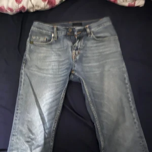 Ljusblå jeans från Tiger of Sweden - 30/32 är storleken och modellen är Pistolero. Säljer ett par ljusblå jeans från Tiger of Sweden med klassisk femficksmodell och snygga kontrastsömmar. Jeansen har raka ben och normal passform, tillverkade i mjukt bomullsjeans-tyg. Perfekta för dig som gillar stilrena och tidlösa jeans.