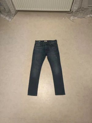 Slim Glenn blå jeans storlek 29/30 - Säljer ett par blå jeans från Slim Glenn i storlek 29/30. Modellen är slim fit med klassisk femficksdesign och snygga slitningar. Jeansen har en rak midja och är tillverkade i jeansmaterial med gul kontrastsöm. Perfekt för dig som gillar en smalare passform.
