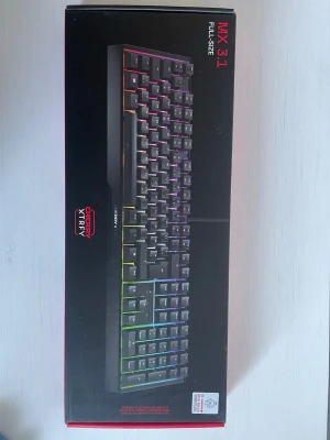 Cherry Xtrfy MX 3.1 Full Size - Cherry Xtrfy MX 3.1 är ett fullstort mekaniskt tangentbord med RGB-belysning och nordisk layout. Utrustat med Cherry MX Red-switchar för snabb respons och tystare användning. Perfekt för gaming och produktivitet. Produkten är i nyskick, levereras i originalförpackning. Oöppnad!