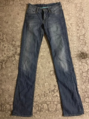 Blå jeans från Mustang, straight fit - Snygga blå jeans från Mustang med klassisk femficksdesign och raka ben. Jeansen har ljusare slitningar framtill och bak, samt detaljerade sömmar på bakfickorna. Materialet är robust denim i bomull och passformen är straight med låg midja. Dm för mått och frågor 💘