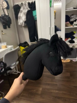 Svart käpphäst med fluffig man - Säljer en svart käpphäst med mjuk och fluffig man. Huvudet är sytt i tyg och har broderade detaljer vid ögonen. Perfekt för dig som gillar att rida och vill ha en stilren och cool häst att träna med eller leka med. Manen är extra tjock och ger ett snyggt uttryck.