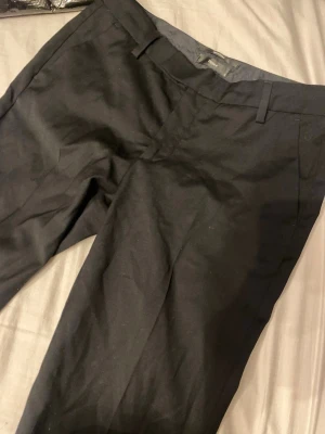 Low waist Svarta kostymbyxor Filippa K XS - Snygga svarta kostymbyxor från Filippa K i storlek XS. Klassisk rak passform med bälteshällor och diskreta bakfickor. Perfekta för en clean och stilren look. Materialet känns mjukt och har en lätt stretch för extra komfort.