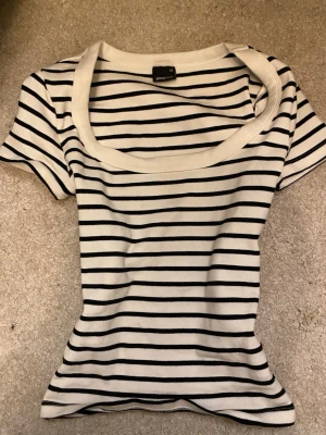 Randig topp från Gina Tricot XS - Helt ny aldrig använts🥰Säljer en vit och svart randig topp från Gina Tricot i storlek XS. Toppen har rund halsringning och korta ärmar. Materialet är mjuk bomull med stretch och passformen är slim. Perfekt för dig som gillar klassisk stil med en modern twist.