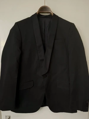 Smoking kavaj - J.Lindeberg - Stl 46 - Svart smoking kavaj från J lindeberg, slim. Snygga slag och diskreta knappar.  Använd 1 gång, och helt utan anmärkningar.  Nypris 3500.