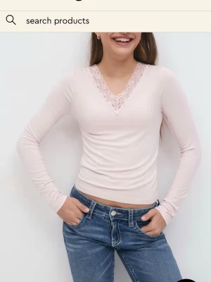 Ljusrosa långärmad topp med spets - Supersöt ljusrosa långärmad topp från Gina Tricot med v-ringning och fina spetsdetaljer längs halsen. Sitter snyggt och är perfekt att styla med jeans eller kjol. Mjuk och skön i materialet. 