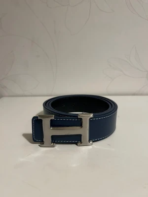 H Bälte blå - Helt nya & högkvalitativa bälten till låga priser! Välj bland olika märken, mönster och färger. Vi fraktar din order så snabbt  som möjligt och vi ser till att ditt paket är säkert packat under frakt 🚚 