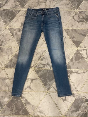 Replay Anbass Hyperflex jeans blå - Säljer ett par Replay Anbass Hyperflex jeans i klassisk blå tvätt. Modellen har smal passform, fem fickor och snygga detaljer på bakfickorna. Stretchigt material som gör dem riktigt sköna att ha på sig. Perfekt för dig som gillar stilrena och moderna jeans.