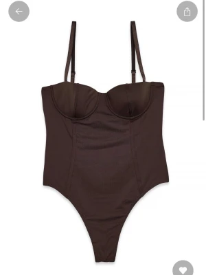 Brun korsett microbody - Snygg brun korsett microbody med bygel och hög skärning. Bodyn enfärgad har tight passform som framhäver siluetten. Materialet är mjukt och stretchigt syntet. 