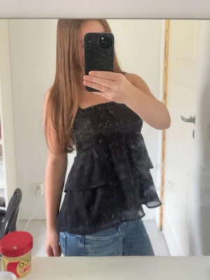 Svart volang topp💗 - en svart volang topp💓 är axelbandslös och ger en flowy look💕 materialet känns lätt och har en snygg fall💗 säljs på grund av att den inte kommer till användning, däremot mycket fint skick💕