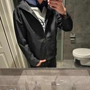 Svart vindjacka med huva från Zara  - Svart vindjacka med huva och dragkedja framtill. Riktigt snygg och praktisk. Jackan är i storlek S/M. Den är i riktigt bra skick. Hör av er vid funderingar:)