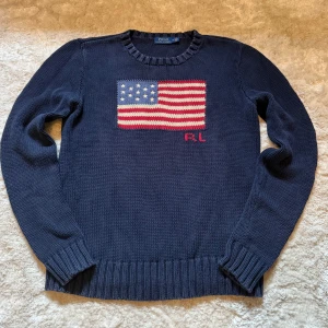 Ralph Lauren tröja - Säljer en klassisk Polo Ralph Lauren stickad tröja med den ikoniska amerikanska flaggan på bröstet. En riktig Ralph Lauren-ikon som aldrig går ur tiden.  ✅ Märke: Polo Ralph Lauren ✅ Färg: Marinblå ✅ Mått: [skriv privat] ✅ Storlek: [M men passar S] ✅ RL-brodyr under flaggan ✅ Bekväm och tidlös modell – passar året runt  Tröjan är i fint begagnat skick, mjuk och skön med exklusiv känsla. En favorit för dig som gillar klassisk preppy-stil med en amerikansk touch.  📌 Nypris ligger oftast runt 3000-