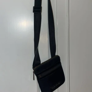 Svart axelväska från Valentino - Snygg svart axelväska från Valentino med justerbart band och flera fack. Bra skick, 7/10. Storlek one-size.