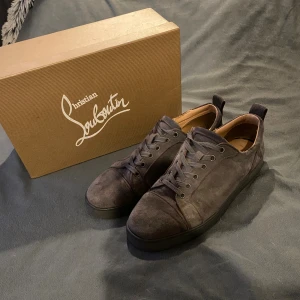 Gråa Louboutin skor - Säljer ett par grå skor från Christian Louboutin i lyxig mocka med klassisk röd sula. Skorna har rund tå, snörning och diskret design som passar till allt. Kommer med originalkartong, dustbag och äkthetskort. Perfekta för dig som gillar exklusiva detaljer. Sulan i hälen är lite sunkig annars fins skor passar till nästan allt, bara höra av sig vid funderingar 