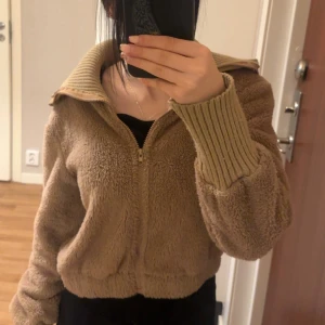 Beige teddyjacka från SHEIN XS - Mysig teddyjacka i beige från SHEIN, storlek XS. Jackan har en bred ribbad krage och muddar, dragkedja framtill och är tillverkad i mjuk fleece. Perfekt för dig som gillar chill och comfy vibes. Snygg att styla med jeans eller leggings.