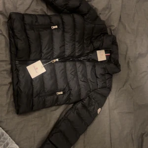 Svart pufferjacka från Moncler - Tja, jag säljer en förtjusande moncler jacka perfekt för en kall vinter dag här i Sverige. Jackan kommer med en päls luva men den kan man ta bort och sätta på beror helt enkelt på ditt humör. Jackan är i svart tveka inte ställ era frågor. Priset är inte hugget i sten!! Jackan är inte använd en endaste gång 