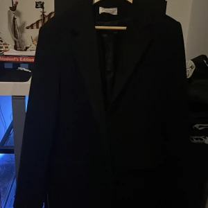 Svart kappa från Pier One - Manlig, svart kappa från Pier One i storlek M.  Har nyligen köpt en ny kappa och därför bestämt mig för att göra mig av med denna. Varsamt använd och är i gott skick!  Material: Ullblandning