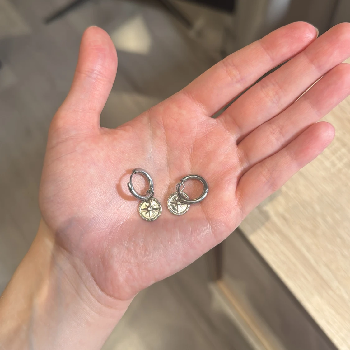 Silverfärgade örhängen med kompassberlock