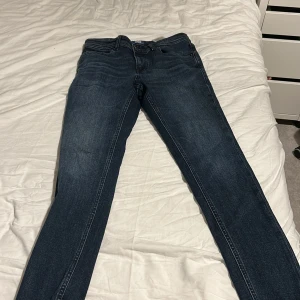 Mörkblå skinny jeans från Jack & Jones - Snygga mörkblå jeans från Jack & Jones med klassisk femficksdesign och skinny passform. Jeansen har en smal siluett, normal midja och är tillverkade i stretchigt denim för extra komfort. Perfekt för dig som gillar en modern och stilren look. Knappt använda använda kanske 3 gånger