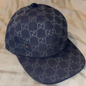 Gucci keps med GG-mönster - Snygg keps från Gucci i mörkblå med det klassiska GG-monogrammet över hela kepsen. Skärmen är böjd och materialet är kraftig bomullscanvas. Perfekt för dig som vill ha en exklusiv och trendig accessoar med tydlig logga.