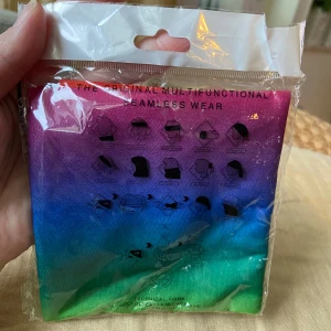 Multifunktionell halsduk i regnbågsfärger - Helt ny i obruten förpackning! Halsduk/bandana som man kan knyta på många olika sätt, se bilderna på förpackningen. Säljer en multifunktionell sömlös halsduk i snygga färgskiftningar från rosa och lila till blått och grönt. Perfekt som accessoar till träning eller uteliv. Tillverkad i mjuk polyester som andas och är lätt att bära på flera olika sätt.