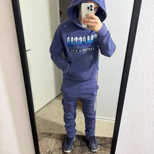 Trappstädning Tracksuit - Väldigt skön tracksuit som har en bakficka på höger ben och en ficka på hoodien. Håller dig varm och bekväm i kallt väder. Storlek S men passar bra till M