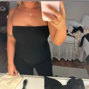 Svart stickad tubtopp från Gina Tricot - Säljer en svart stickad tubtopp från Gina Tricot i storlek XS. Toppen är bandeau-modell, ribbstickad och sitter tight över kroppen. Perfekt att styla med höga jeans eller kjol för en clean look.