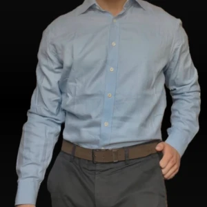 Ljusblå skjorta från Oscar Jacobson - Snygg ljusblå skjorta från Oscar Jacobson med diskret rutigt mönster. Klassisk krage, långa ärmar och vita knappar framtill. Tillverkad i 100% bomull med double yarn count för extra komfort. Perfekt för dig som gillar stilrena och tidlösa plagg.