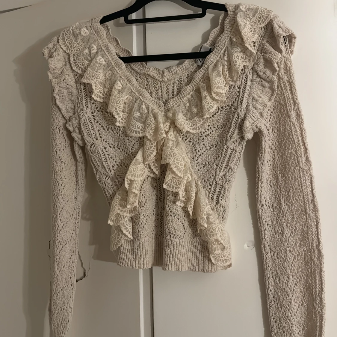 Beige stickad tröja med spetsvolanger