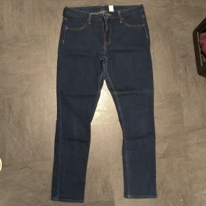 Mörkblå skinny jeans &Denim stl 31 - Säljer ett par mörkblå skinny jeans från &Denim i storlek 31. Modellen är ankle length med regular waist och klassiska fem fickor. Materialet är en mix av bomull, polyester, viskos och elastan för en stretchig och bekväm passform.
