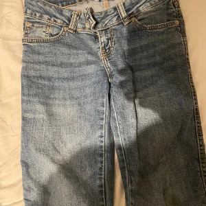  ljusblå jeans - Ljusblå jeans med klassisk femficksdesign och raka ben. Jeansen har kontrastsömmar och dubbla knappar i midjan. Perfekta för dig som gillar en tidlös denimlook.