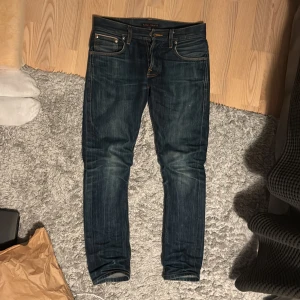 Selvedge Nudie Jeans - Säljer ett par selvedge jeans från Nudie Jeans.  Modell: Grim Tim Storlek: W27 L30                           Färg: Organic Dry Selvage De är i bra skick men det finns tecken på användning. De har blivit tvättade ett fåtal gånger för att uppnå dessa sjukt snygga fades. Kan tvättas innan köp om så önskas. De har najs honeycombs, whiskers och fades överlag. Även slitning vid backfickan vilket ger en “vintage” look.  Skriv vid frågor!