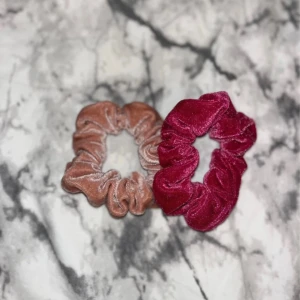 2-pack scrunchies i sammet - Två scrunchies i mjuk sammet, en i vinröd och en i ljusbrun. Perfekta för att ge din frisyr extra volym och en lyxig touch. Båda har en glansig finish och är riktigt sköna att bära, passar både till utsläppt och uppsatt hår.