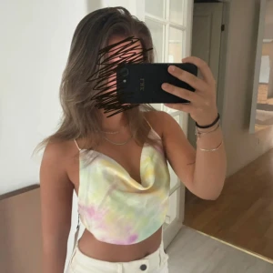 Pastellfärgad silkestopp från Zara - Säljer en superfin pastellfärgad silkestopp från Zara i storlek XS. Toppen har tunna axelband, draperad urringning och öppen rygg med snörning. Materialet är glansigt och känns lyxigt, perfekt för varma dagar. Ny med prislapp!