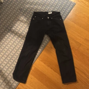 Svarta jeans från Tiger of Sweden - Svarta jeans från Tiger of Sweden med klassisk femficksdesign och raka ben. Jeansen har en stilren look med svarta sömmar och diskret läderpatch bak i midjan. Tillverkade i ett mjukt jeanstyg som sitter snyggt och passar till många olika stilar.