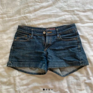 Mörkblå jeansshorts från &NOW: W27 - Klassiska mörkblå jeansshorts från &NOW: i storlek W27. Modellen har normal passform, fem fickor och uppvikta benslut. Perfekta för sommaren och lätta att matcha med allt. Gjorda i bomull för en skön känsla.