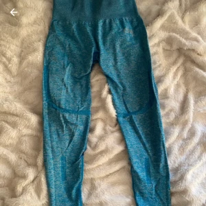 Blå träningstights i meshdetalj M - Säljer ett par blå träningstights i storlek M men skulle mer säga att det passar s, med snygga meshpaneler på baksidan av benen. Tightsen har hög midja och är tillverkade i ett stretchigt syntetmaterial som andas. Perfekta för gymmet eller löprundan. 