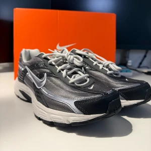 Nike Initiator Sneakers - Grå/Silver- EUR 43-Helt Ny - Säljer ett par Helt nya Nike Initiator sneakers i en stilren grå och antracit färgkombination. Skorna kommer i originalkartongen.  Skorna är helt nya och aldrig använda. Perfekta för löpning och träning, men passar lika bra till vardags.  EUR 43  Färg: Grå/Silver