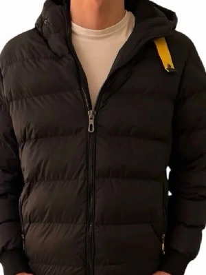 Svart dunjacka från Parajumpers - Snygg svart dunjacka från Parajumpers med huva och gul detalj vid halsen. Jackan har dragkedja framtill, två sidofickor och ett tydligt PJS-märke på ärmen. Perfekt för kalla vinterdagar och riktigt skön att bära.