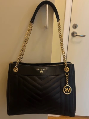 Michael Kors väska -  Michael kors väska  100 % äkta och kommer med originalpåse. Inga repor, inga märken, helt som ny aldrig använd.  Svart quiltad modell med gulddetaljer köpt för 3500  pris går diskuteras :) 