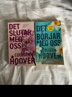 Det slutar med oss & Det börjar med oss - Två populära romaner av Colleen Hoover: 'Det slutar med oss' med lila omslag och blommotiv samt 'Det börjar med oss' med blått omslag och blommor. Båda är pocketböcker på svenska från Lovereads, perfekt för dig som gillar starka känslor och relationer.