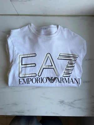 Armani tröja - Vit långärmad topp från Emporio Armani med stort svart EA7-tryck framtill. Storlek L funkar M oxå, gammal modell säljs ej mer ! 