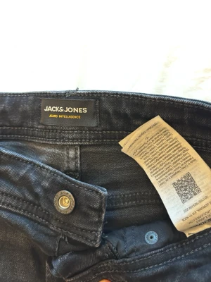 Svarta jeans från Jack & Jones - Snygga svarta jeans från Jack & Jones med klassisk femficksdesign och raka ben. Jeansen har metallknapp med logga och är tillverkade i ett mjukt denimtyg som sitter skönt hela dagen.