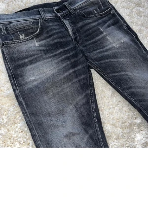 Dondup jeans - Snygga svarta slim fit jeans med slitningar och tvättade detaljer. Jeansen har klassisk femficksdesign och dragkedjegylf. Perfekta för en trendig och avslappnad look.