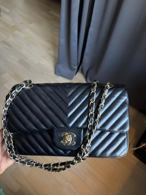 Svart handväska  - Säljer en svart axelväska som är väldigt rymlig och passar till allt. Den har röd klädsel invändigt. Det är en kopia.