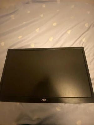 AOC svart datorskärm - Säljer en svart datorskärm från AOC med stilren, rektangulär design. Skärmen har tunna kanter och är tillverkad i plast. Perfekt för gaming, studier eller arbete vid datorn.